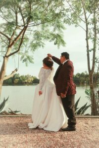 bride and groom in formal attire dancing near the water